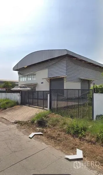 Warehouse for rent in Lam Luk Ka, Pathum Thani - Modern metal-clad warehouse with curved roof, gated entrance and ramp in Lam Luk Ka.
