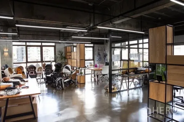 Office Space for rent in Khlong Toei, Bangkok - Open-plan industrial office with polished concrete floors, glass partitions, wood-and-metal shelving, and large windows with city views.