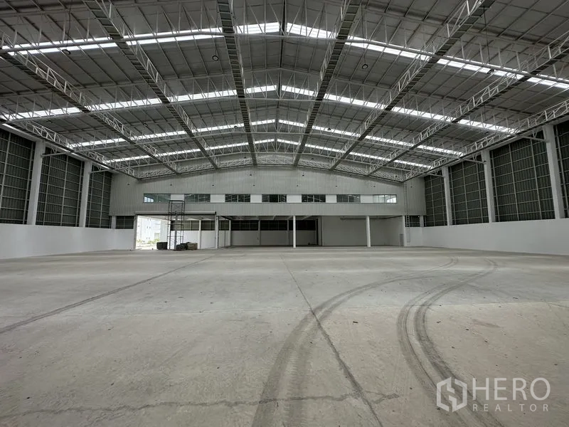 Factory for rent in Pathum Thani - Factory floor with tire marks facing the central mezzanine and loading bays.
