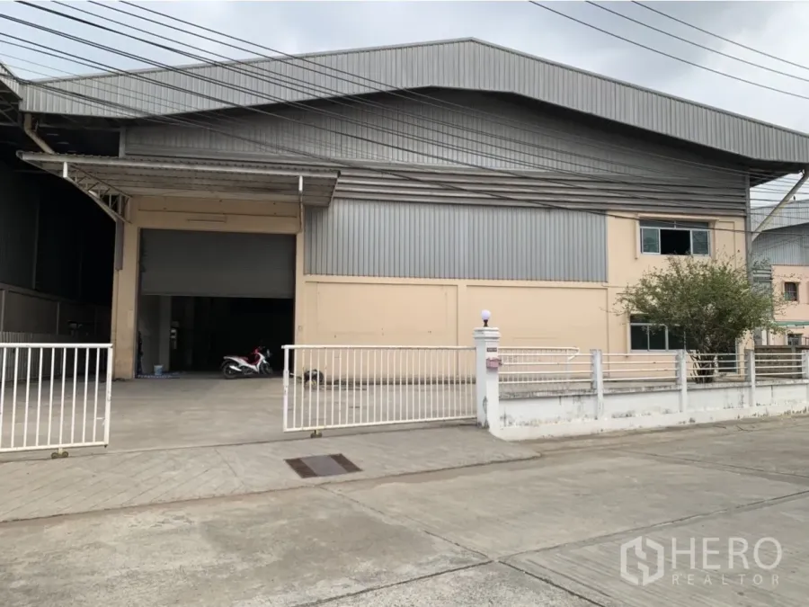 工厂 出租在Mueang Samut Prakan, Samut Prakan - 工厂外立面，金属板结构，带大门与宽敞车道及遮雨装卸区。