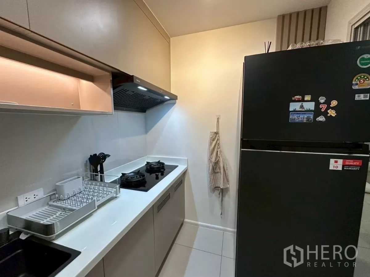 Townhouse for rent in Saphan Sung, Bangkok - Galley kitchen angle showing two-burner gas stove, long countertop and refrigerator.