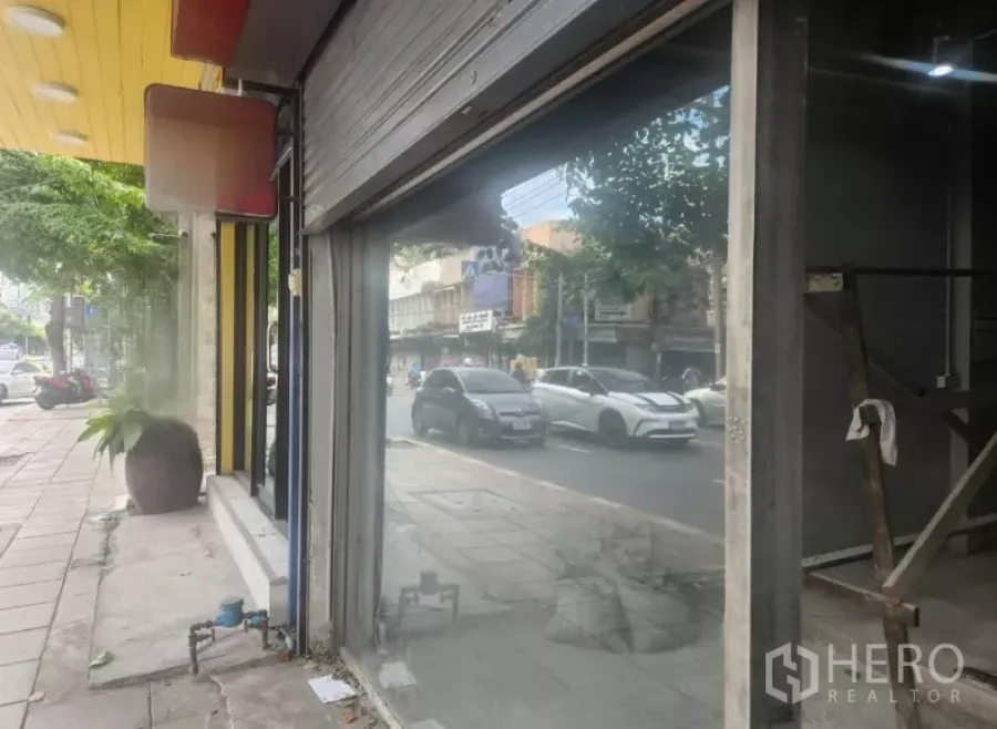 Shophouse for rent in Watthana, Bangkok - Ground-floor glass frontage of a shophouse facing a busy Ekkamai road with a wide sidewalk.