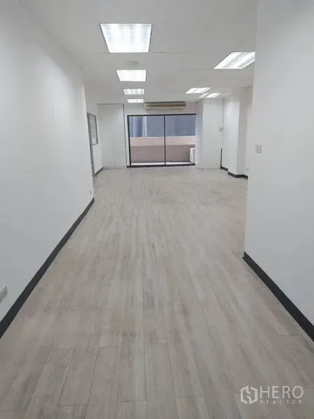 Office Space for rent in Pathum Wan, Bangkok - Bright open-plan office with wood-look floors, recessed lighting and sliding glass doors to a balcony.