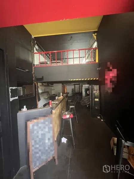 店屋 出租在Khlong Toei, Bangkok - 一层室内带长吧台与高脚椅，顶部为工业风深色天花及夹层