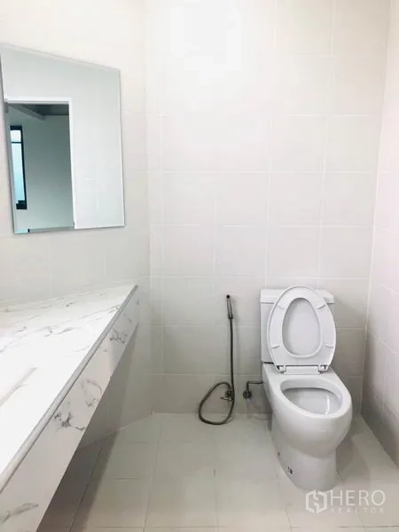 带办公室的家 出租在Khlong Toei, Bangkok - 简约白色卫浴，坐便器、冲洗喷枪及大理石台面。