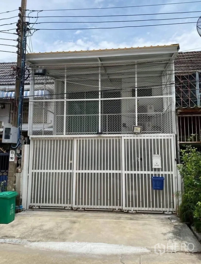 ทาวน์เฮาส์ for rent in Phra Khanong, Bangkok - ด้านหน้าทาวน์เฮ้าส์มีกำแพงรั้วเหล็กสีขาวและซุ้มตะแกรงชั้นบน