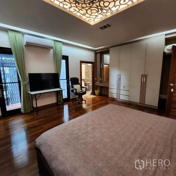 独立式住宅 出售在Phra Khanong, Bangkok - 卧室配内置衣柜、书桌和电视，带阳台门与空调