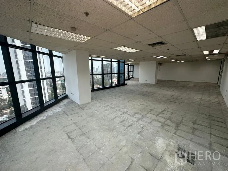 办公空间 出租 - 明亮未装修办公区，网格吊顶、日光灯与全景落地窗，高层视野开阔。