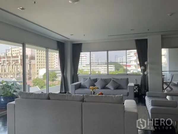 Apartment for rent in Sathon, Bangkok - Corner lounge with grey sofas and panoramic windows overlooking Sathorn.