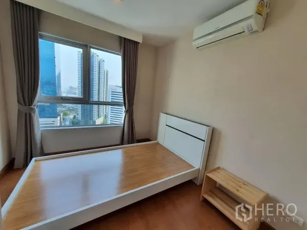 คอนโด ให้เช่าในHuai Khwang, Bangkok - ห้องนอนรองพร้อมเตียงเฟรมไม้ หน้าต่างบานใหญ่เห็นวิวเมือง และเครื่องปรับอากาศ ในย่านห้วยขวาง