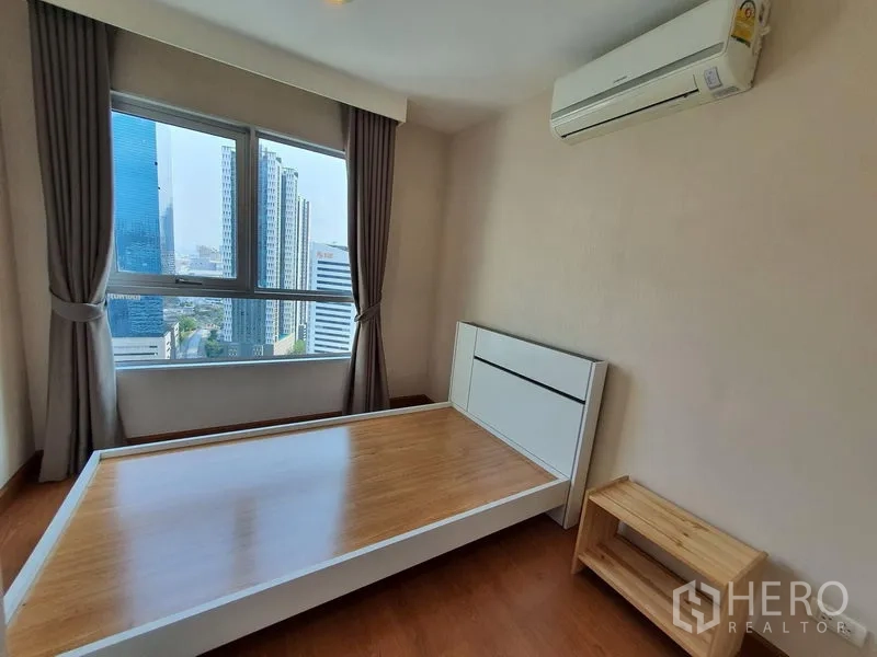 คอนโด ให้เช่าในHuai Khwang, Bangkok - ห้องนอนรองพร้อมเตียงเฟรมไม้ หน้าต่างบานใหญ่เห็นวิวเมือง และเครื่องปรับอากาศ ในย่านห้วยขวาง