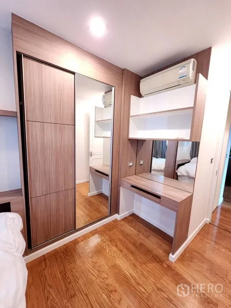 Condominium for rent in Bang Rak, Bangkok - Second bedroom with built‑in wardrobe, mirrored sliding doors and a compact dressing desk.
