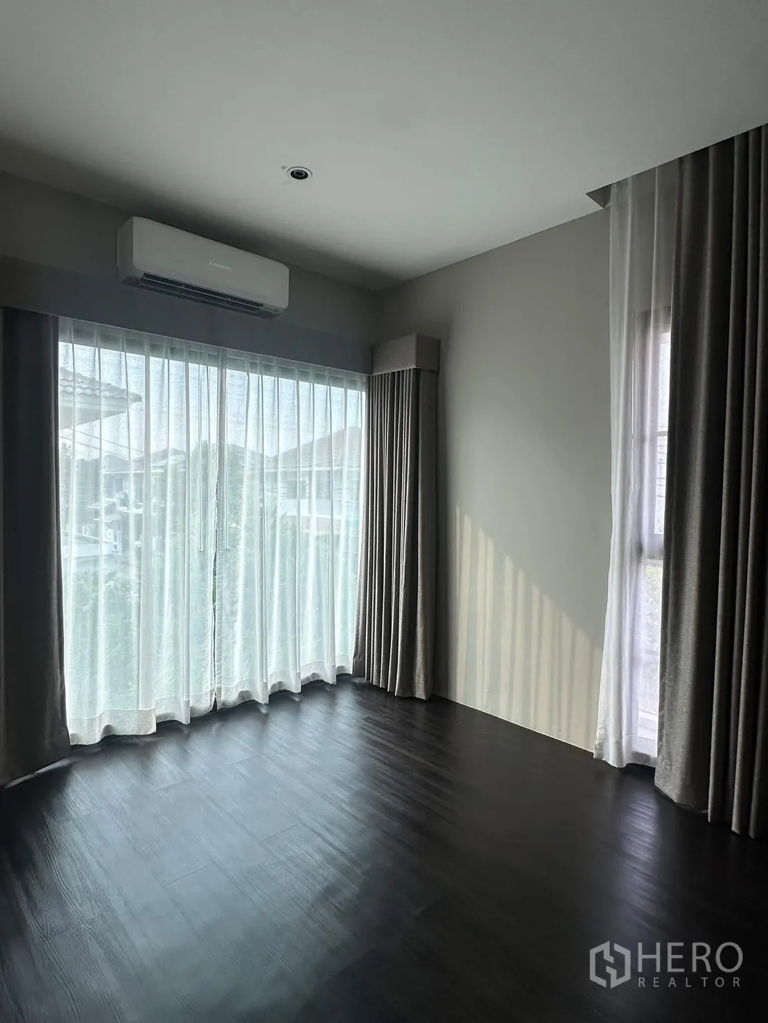 独立式住宅 出租在Lat Krabang, Bangkok - 明亮角落卧室，空调与大窗配薄纱窗帘。