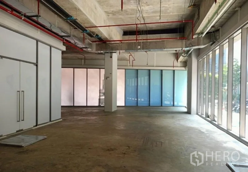 Retail Space for rent in Watthana, Bangkok - Corner view of the retail space showing central column, double doors, and frosted glass panels with abundant natural light.