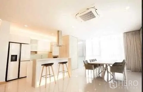 Townhouse for rent in Huai Khwang, Bangkok - Open-plan white kitchen with island breakfast bar and adjacent dining area filled with natural light.