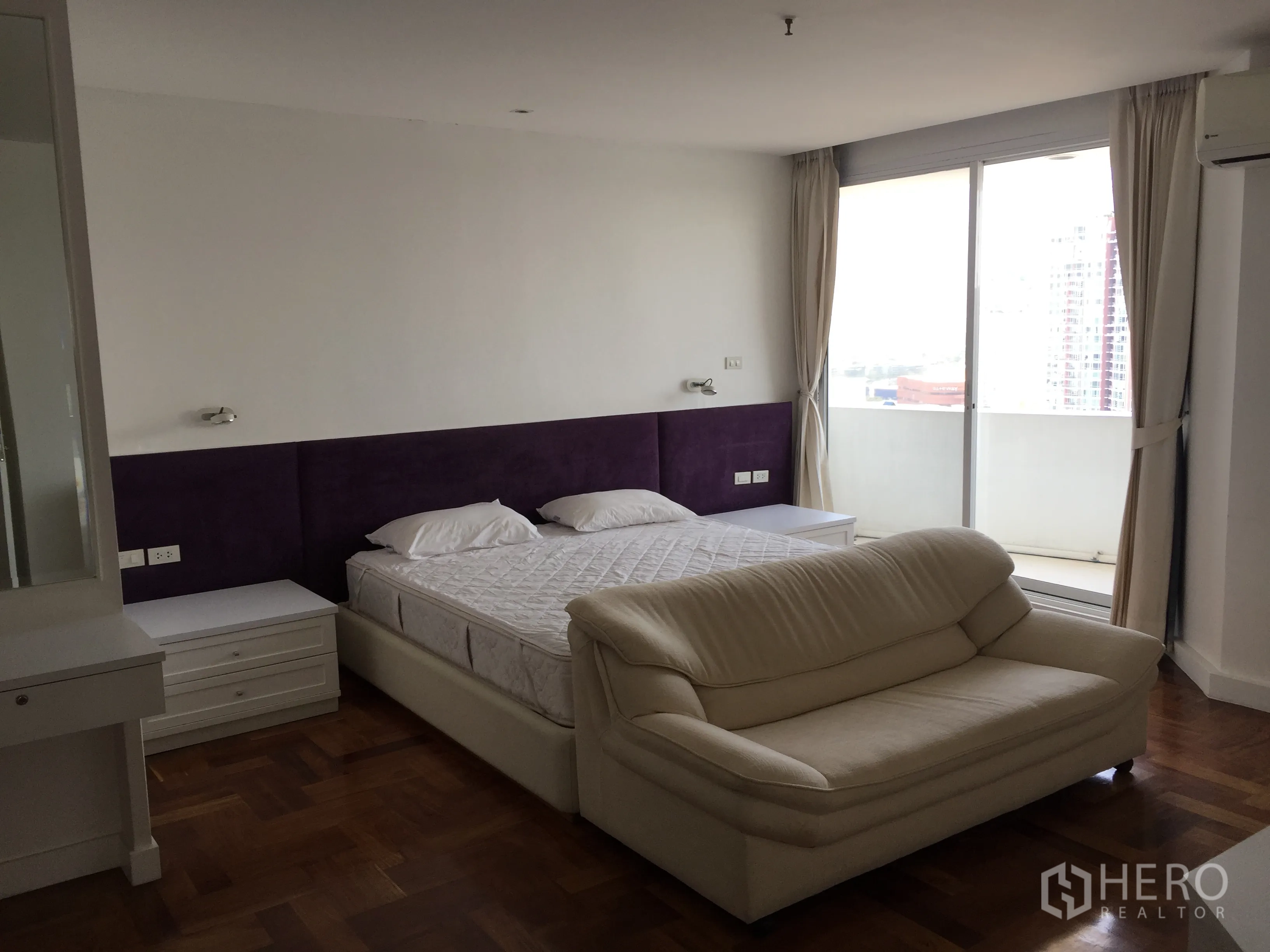 公寓 出租在Watthana, Bangkok - 宽敞主卧，带阳台城市景观与沙发座。