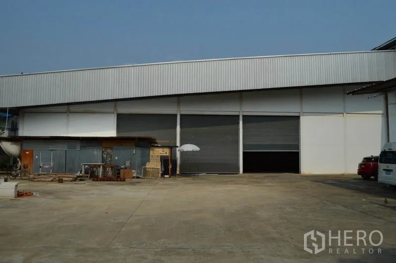 Warehouse for rent in Bang Sue, Bangkok - Industrial warehouse exterior in Bang Sue, Bangkok with multiple roller shutter bays and a wide concrete yard.