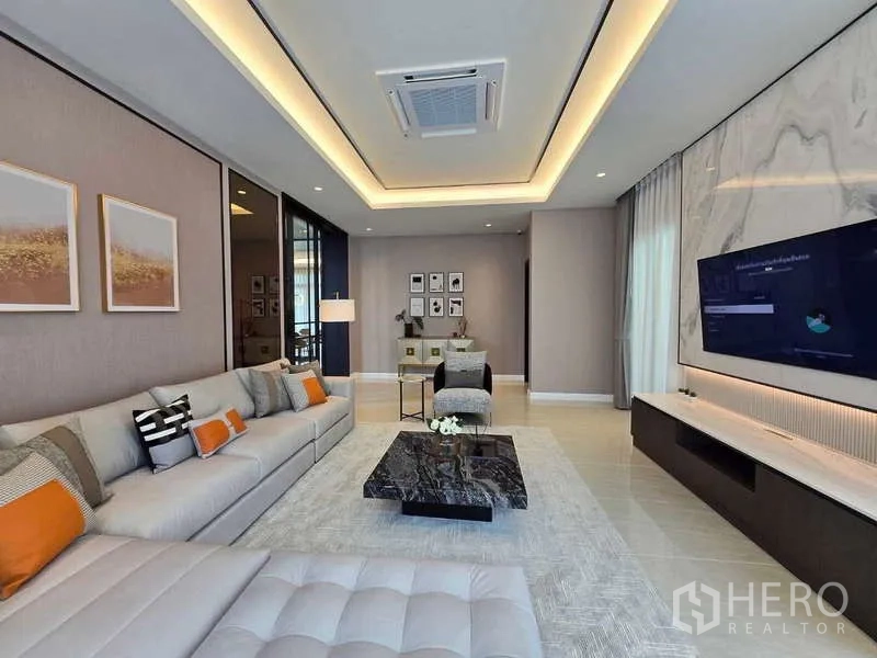 Detached House for rent or sale in Lat Krabang, Bangkok - Family living area with recessed ceiling lighting, TV wall, and marble coffee table.