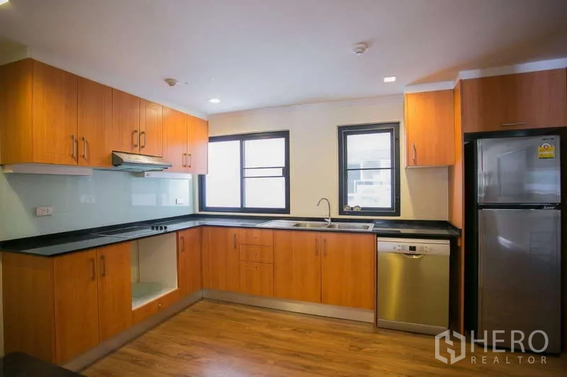 Condominium for rent or sale in Watthana, Bangkok - Full view of U-shaped kitchen with dishwasher, windows and fridge.