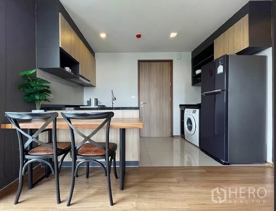 Condominium for rent in Watthana, Bangkok - Kitchen and dining area with fridge and washing machine in an open-plan layout.
