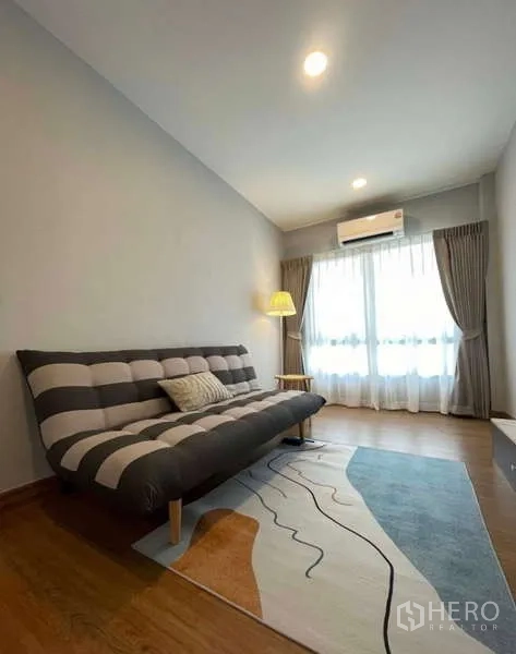บ้าน ให้เช่าในBang Phli, Samut Prakan - ห้องนั่งเล่นเล็กพร้อมโซฟาเบดลายทาง โคมไฟ และประตูกระจกออกระเบียง
