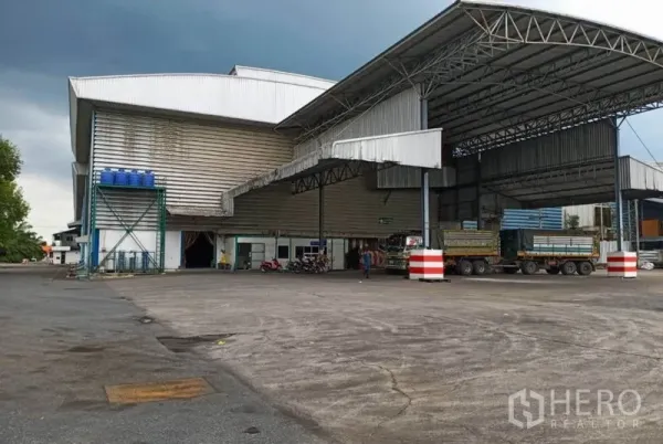 Factory for rent in Ban Phaeo, Samut Sakhon - Covered loading bays with steel canopies and spacious yard suitable for trailer access at the factory.