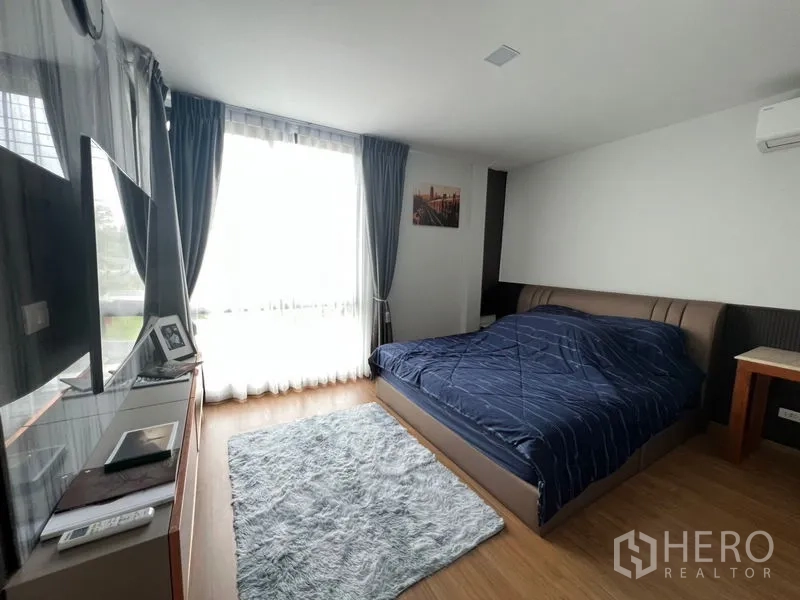 Townhouse for rent - Bright master bedroom with large window, blue bedding, TV console and rug.