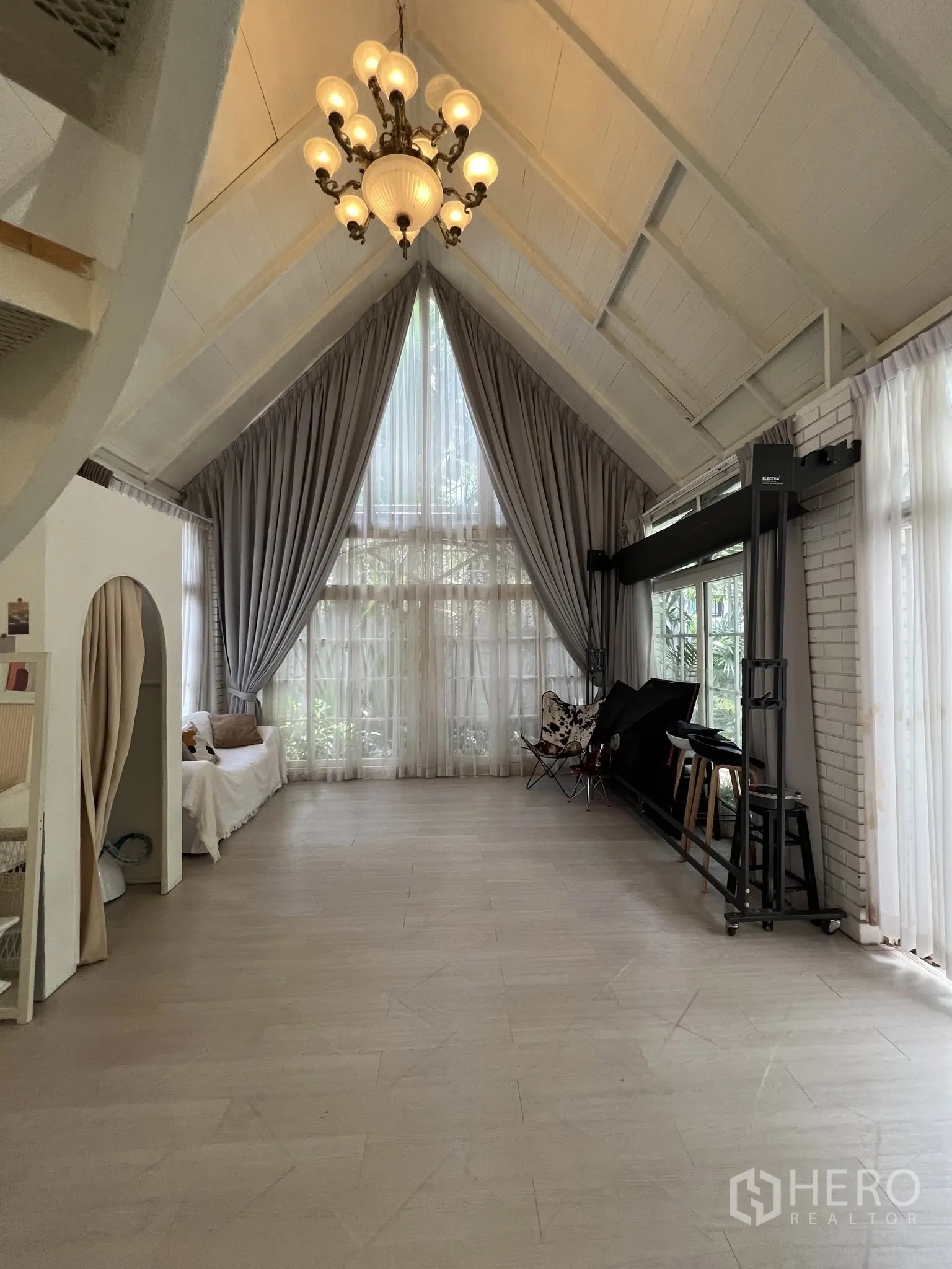 Detached House for rent in Phra Khanong, Bangkok - Large open room with chandelier, pale flooring and draped windows.