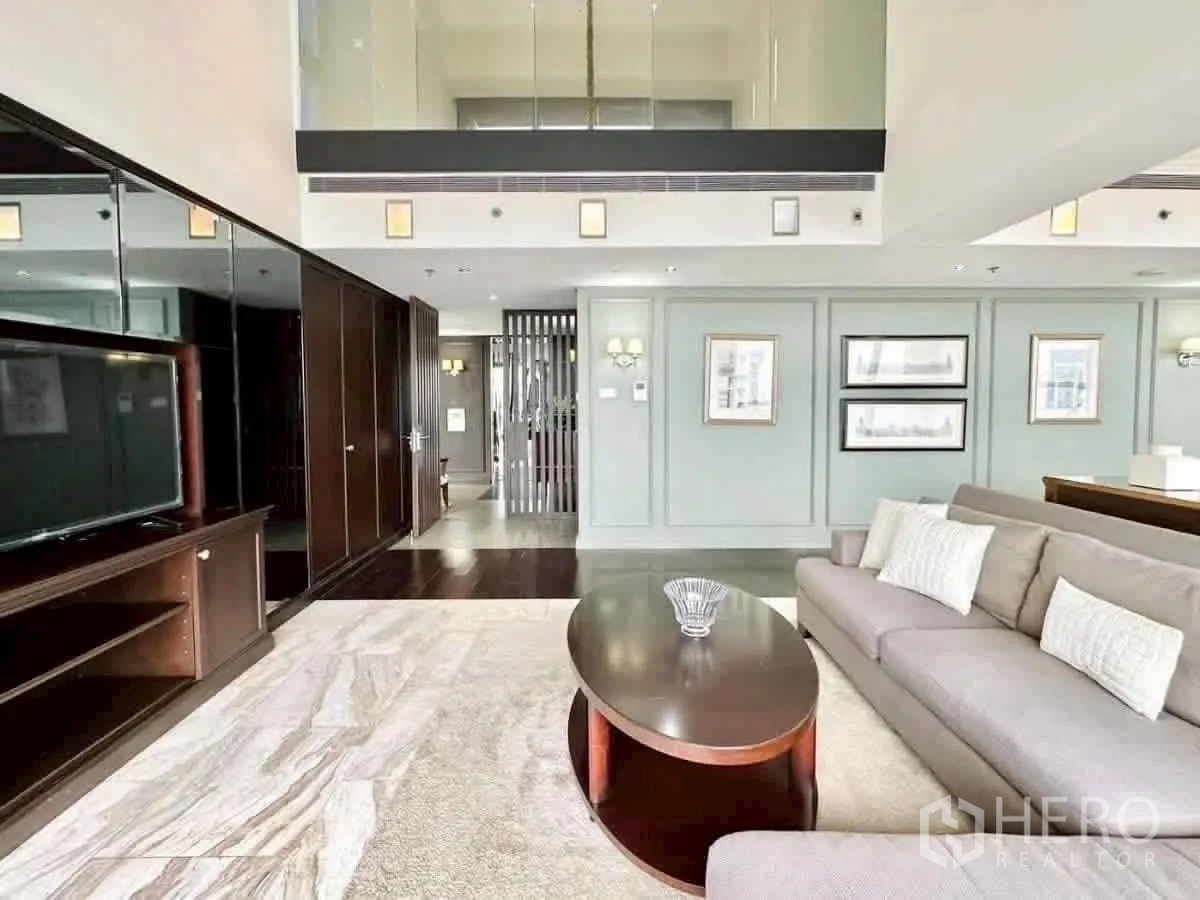 Condominium for rent in Sathon, Bangkok - Bright lounge with double-height ceiling, TV unit and large sofa.
