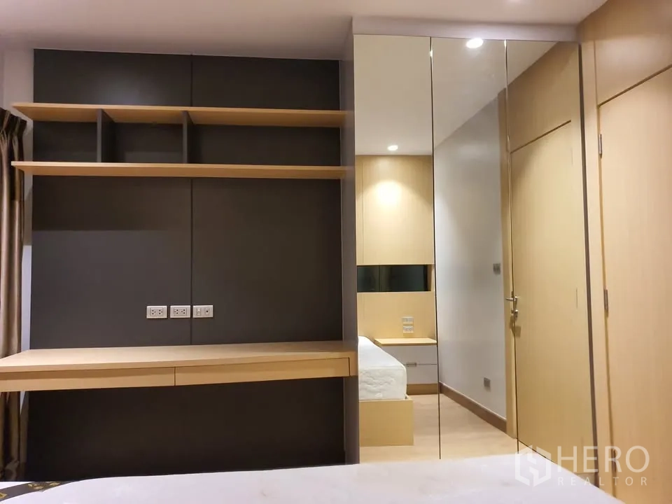 Condominium for rent in Watthana, Bangkok - Bedroom study nook with built-in desk, shelves and a large mirrored wardrobe.