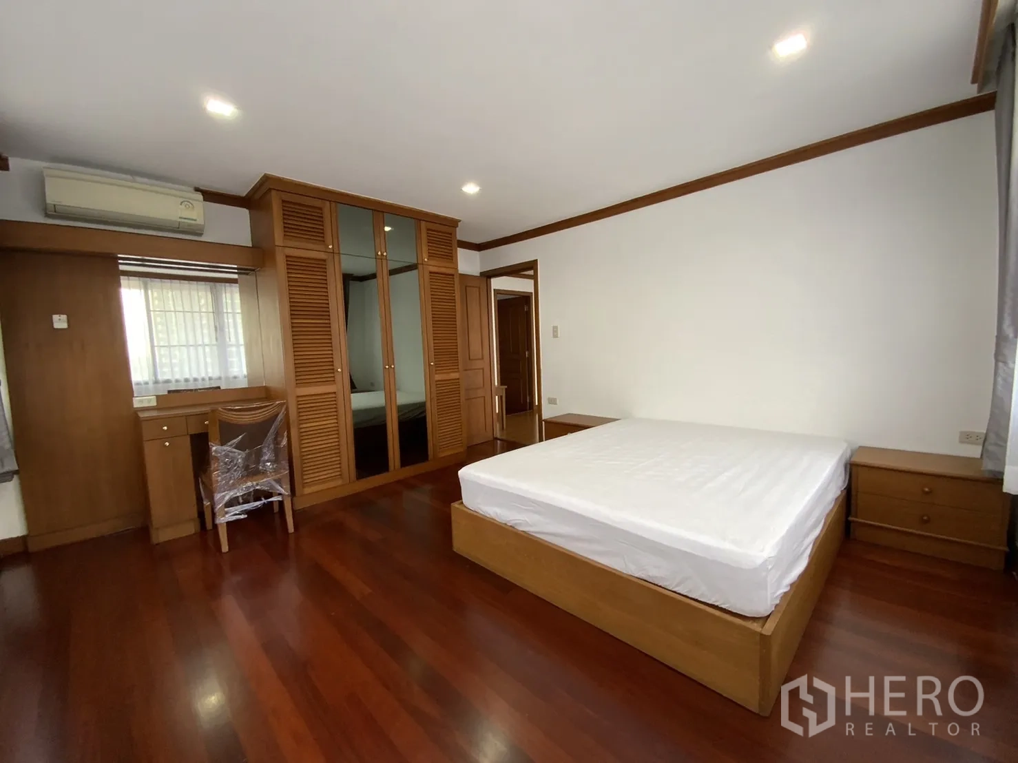 公寓 出租在Watthana, Bangkok - 卧室配双人床、镜面衣柜、书桌和木地板。