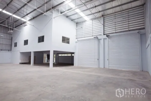Factory for rent in Si Racha, Chon Buri - Factory floor with elevated office block and adjacent roll-up loading doors.