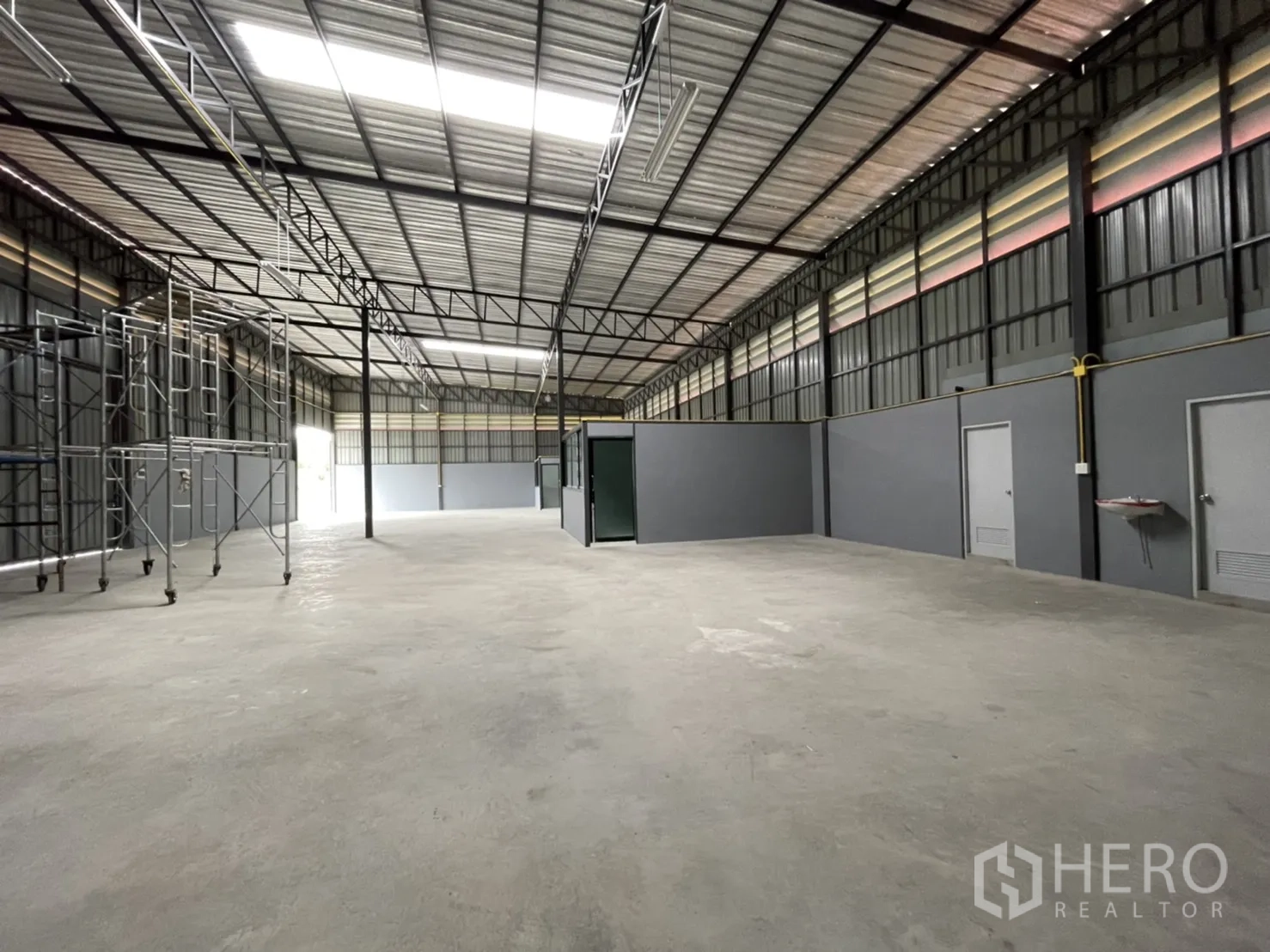 Factory for rent in Khlong Luang, Pathum Thani - Deep view across the factory floor with mobile scaffolding and a central glass-walled office.