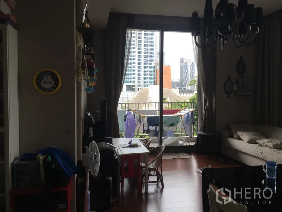 คอนโด ขายในWatthana, Bangkok - ห้องนั่งเล่นและรับประทานอาหารแบบเปิดโล่ง มีโซฟา โต๊ะทานอาหาร และประตูกระจกบานเลื่อนออกสู่ระเบียงวิวเมืองย่านทองหล่อ