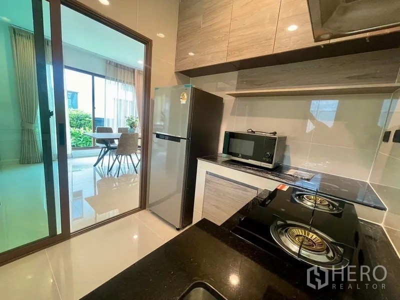 Detached House for rent in Bang Kapi, Bangkok - Separate kitchen with gas hobs, refrigerator and microwave behind sliding door.