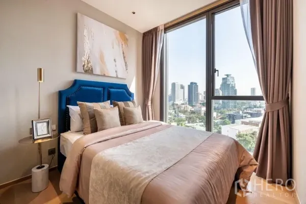 Condominium for rent or sale in Khlong Toei, Bangkok - Second bedroom with large windows, neutral bedding, and skyline outlook over Khlong Toei.