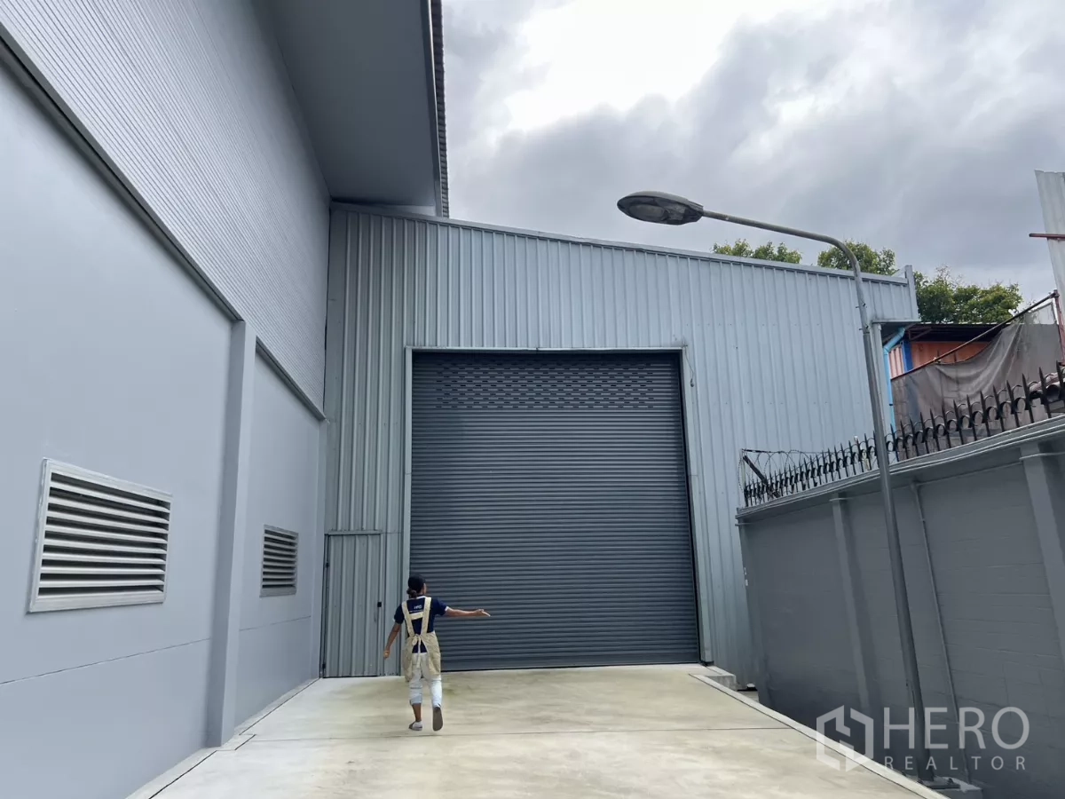 Warehouse for rent in Yan Nawa, Bangkok - Warehouse loading court with an extra‑tall roller shutter beside a secure boundary wall.