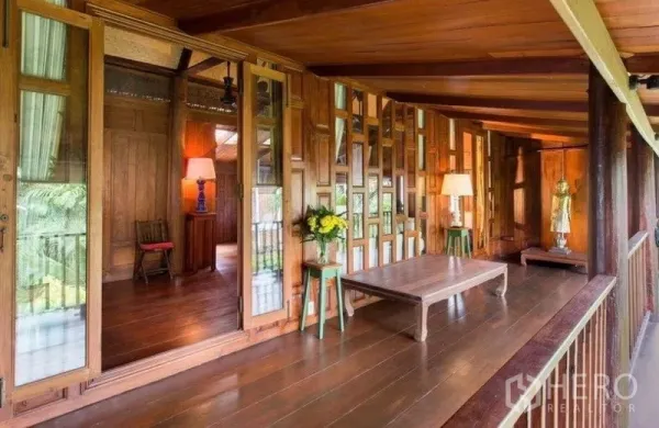 Detached House for rent in Bang Na, Bangkok - Covered wooden balcony with glass‑panel doors, low table and greenery outlook.