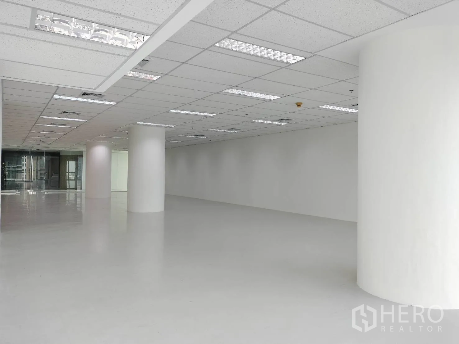 零售空间 for rent in Sathon, Bangkok - 宽敞白色室内空间，圆形立柱与格栅吊顶照明，临玻璃隔断。