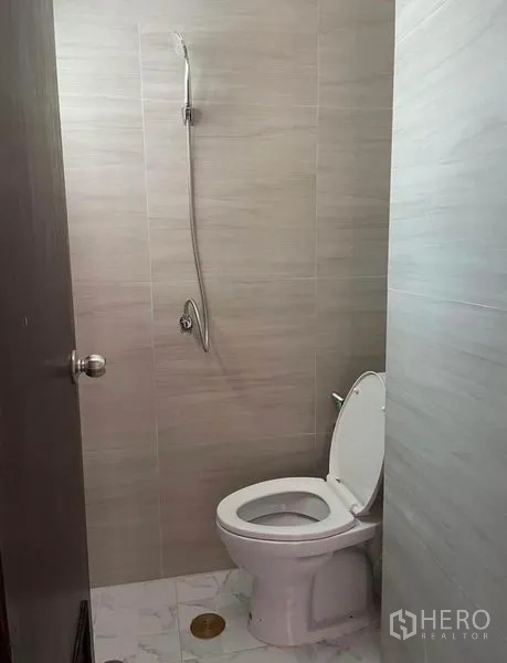 Condominium for rent - Compact bathroom with toilet and handheld shower finished in light tiles.