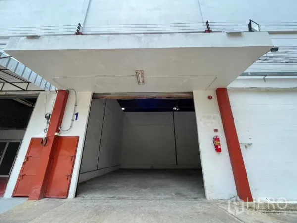 Warehouse for rent in Bang Phlat, Bangkok - Warehouse entrance with wide roller shutter and covered loading bay on an industrial building facade.