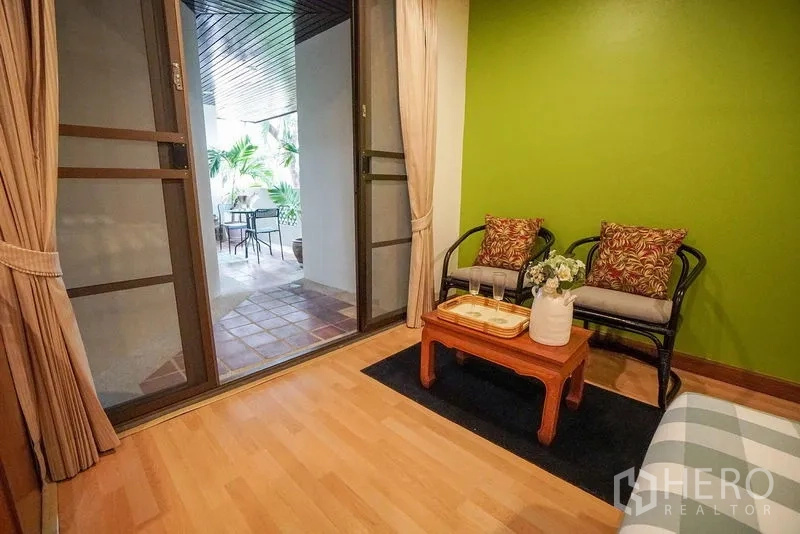 Apartment for rent in Watthana, Bangkok - Cozy balcony sitting corner by sliding doors with garden views.