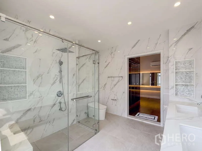 Detached House for rent or sale in Bang Kapi, Bangkok - Luxury bathroom with glass-enclosed rain shower, marble walls and modern fixtures.
