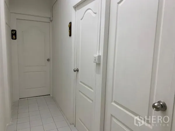 Shophouse for rent in Khlong Toei, Bangkok - Clean white corridor with multiple white panel doors and tiled floor.