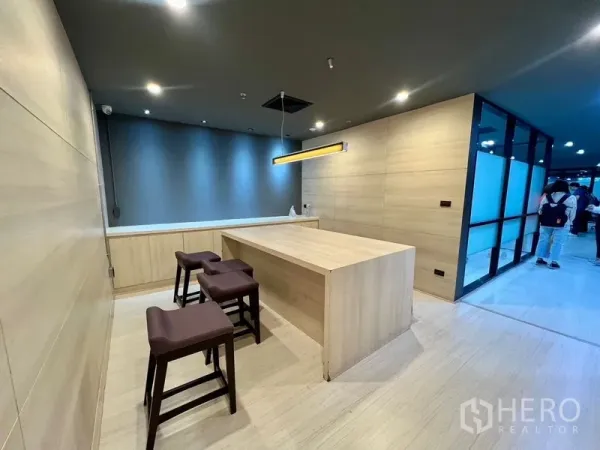 办公空间 出租在Watthana, Bangkok - 茶水区带浅木色中岛、高脚凳与吊灯。