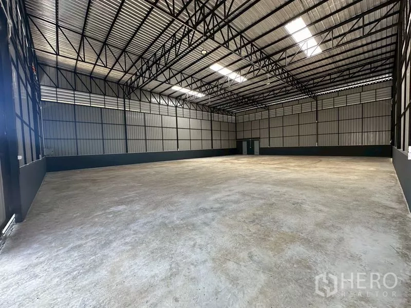 Warehouse for rent in Wang Thonglang, Bangkok - Spacious warehouse interior with high steel truss roof, skylights and durable concrete flooring.