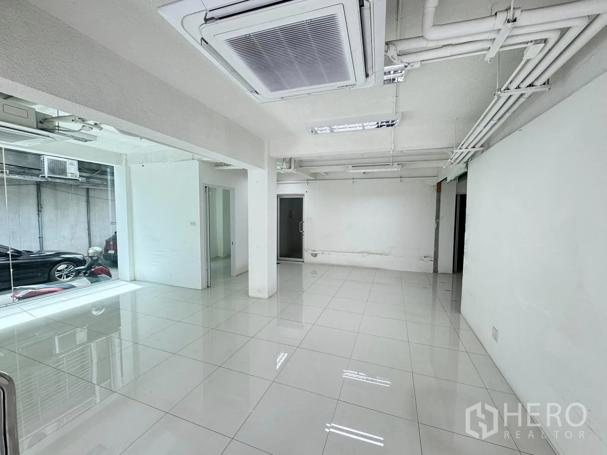 零售空间 出租在Bang Rak, Bangkok - 明亮的开放式零售室内，白色瓷砖地面、整面玻璃门面与嵌入式天花空调。