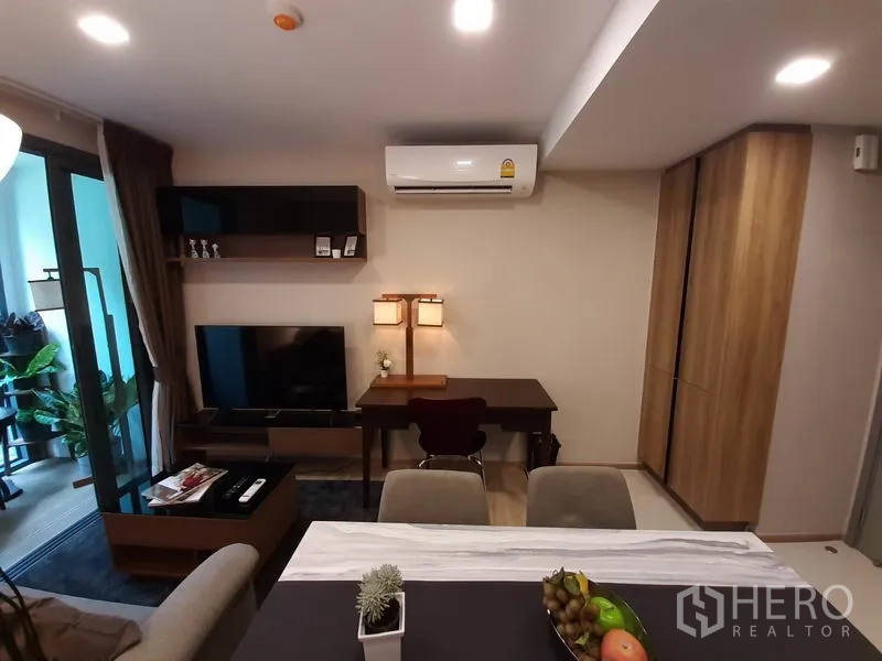 公寓 出租或出售在Watthana, Bangkok - 客厅设壁挂置物架、书桌、电视柜与空调，连接阳台。