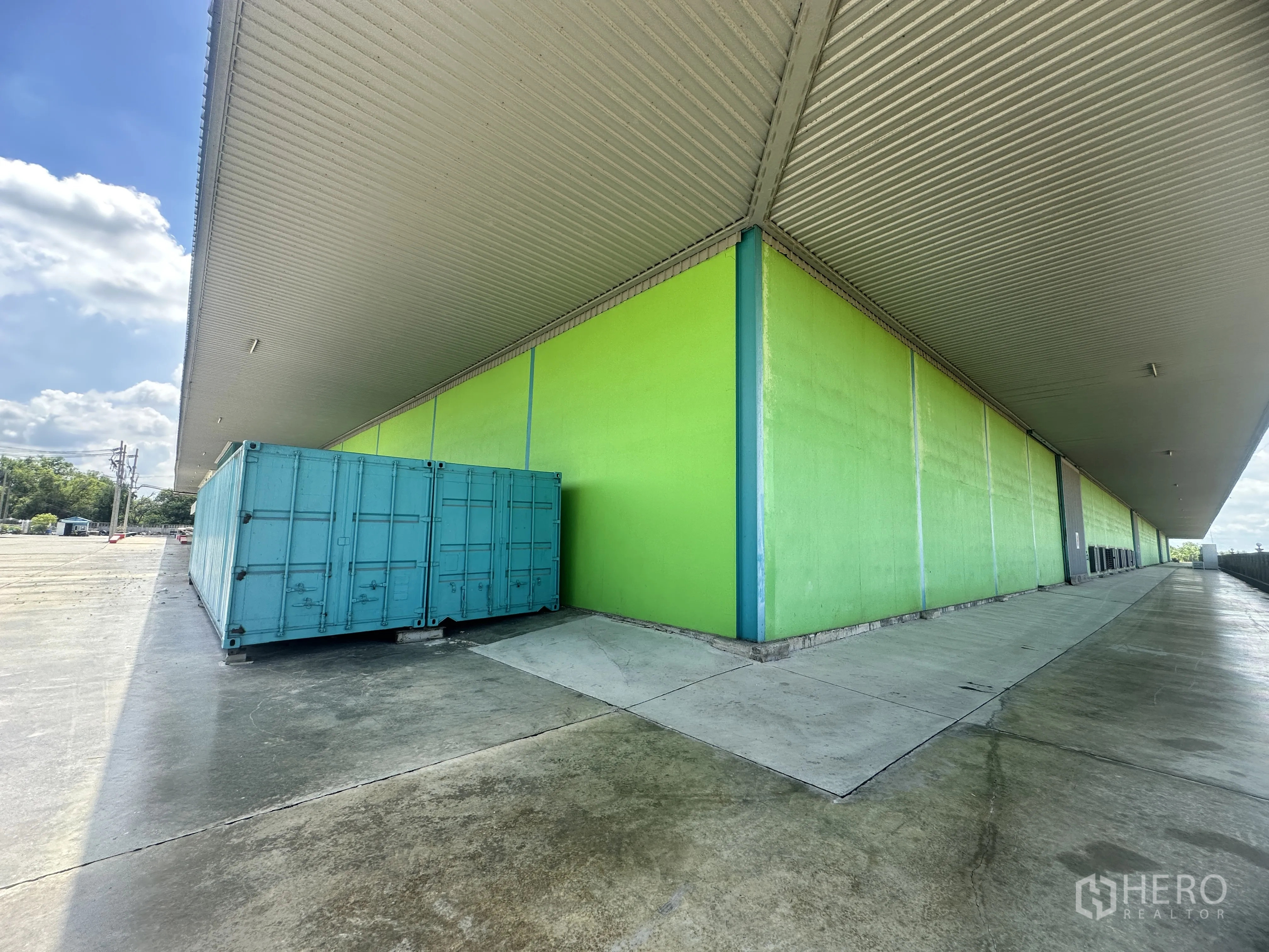 Warehouse for rent in Sai Noi, Nonthaburi - Exterior side of the warehouse with covered loading dock, ramp access, and a shipping container beside the platform.