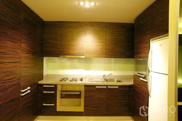 公寓 出租在Watthana, Bangkok - U形厨房，木纹橱柜，嵌入式烤箱与灶台，双槽水盆及冰箱。